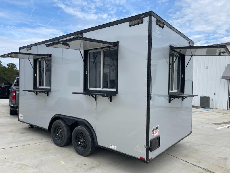 The image shows a large mobile food truck parked outdoors with its windows open, ready for service.