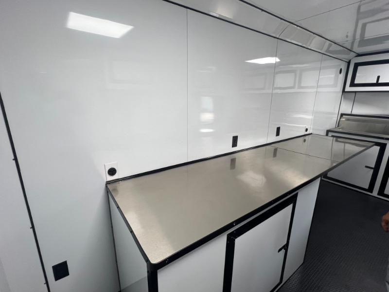 The image shows a commercial kitchen with stainless steel countertops and appliances, featuring a large island table at its center.