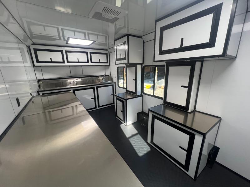 The image shows a modern, well-equipped commercial kitchen with stainless steel surfaces, black countertops, and multiple workstations.