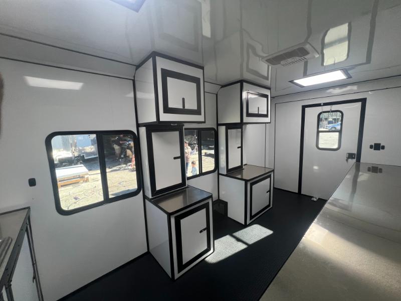The image shows the interior of a recreational vehicle RV with a kitchenette area featuring a countertop, storage cabinets, and a window with black trim.