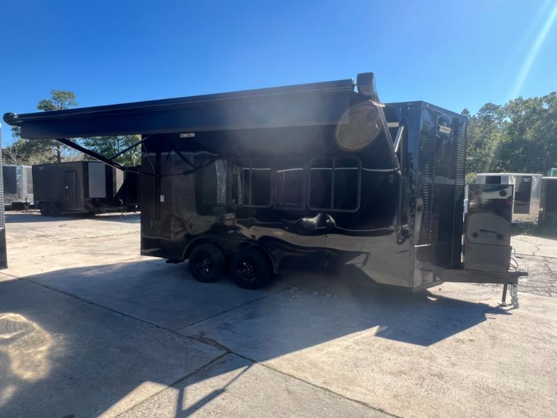 The image shows a large black trailer parked in a lot with a clear blue sky above.
