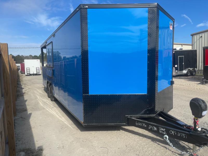 A blue cargo trailer parked on an asphalt surface with a truck visible in the background.