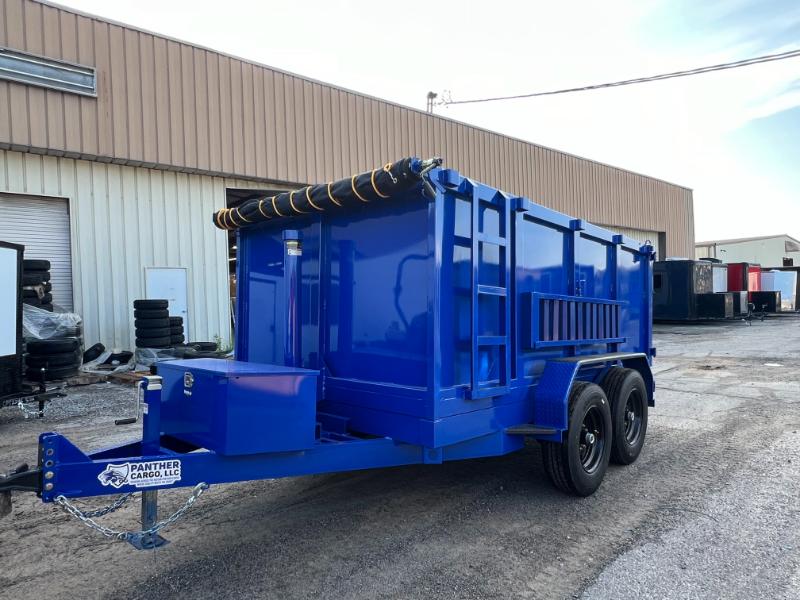 The image shows a blue dump truck parked on a gravel surface with a building in the background.