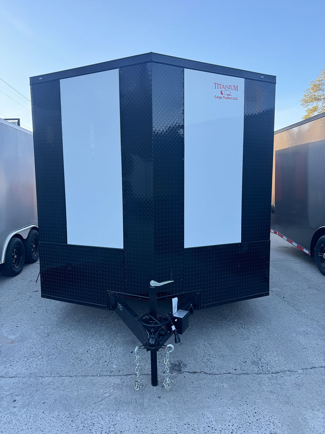 A large black trailer parked on concrete with a white sign on its side.