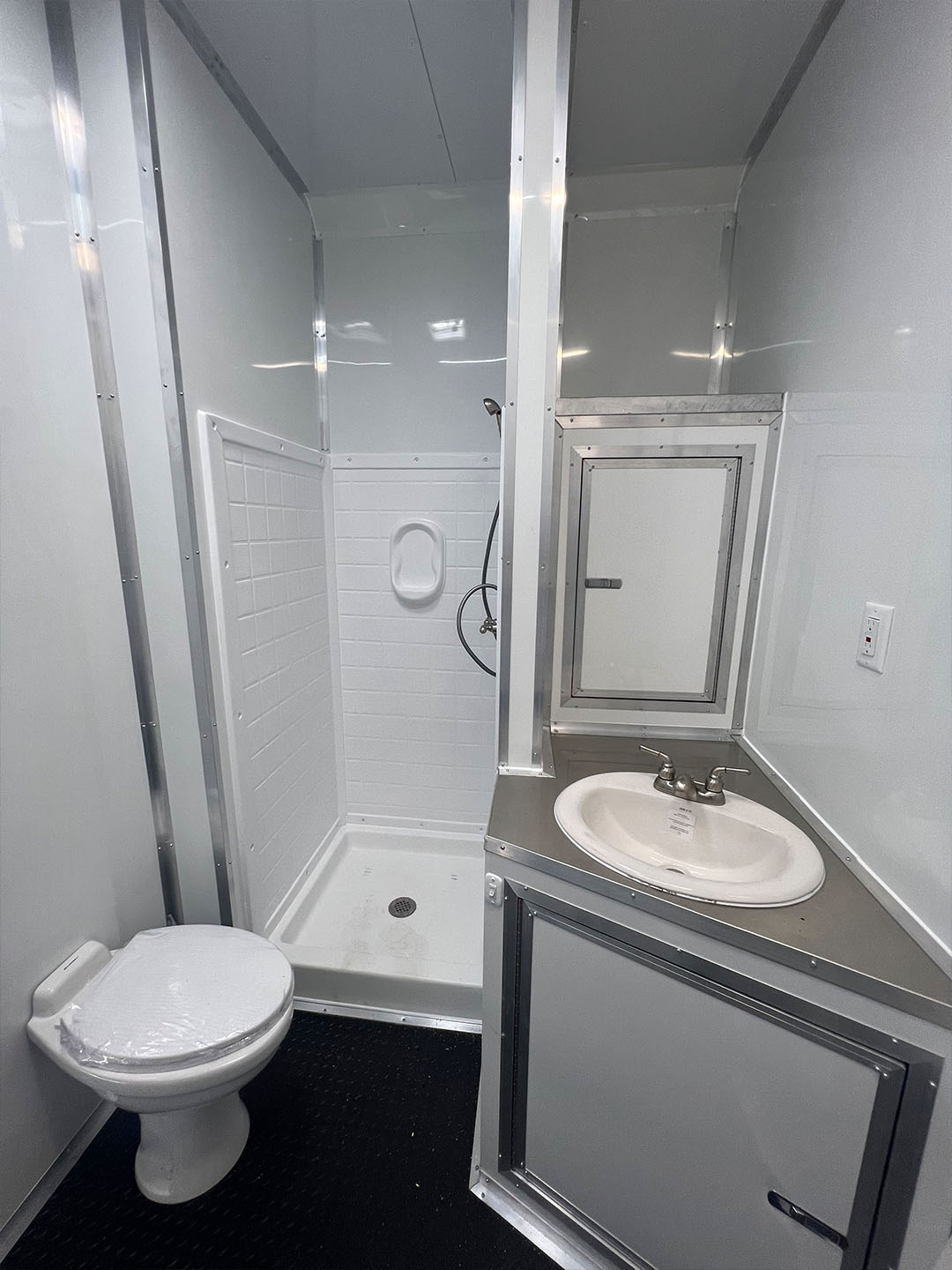 The image shows a small, compact bathroom with a toilet, sink, and shower area.