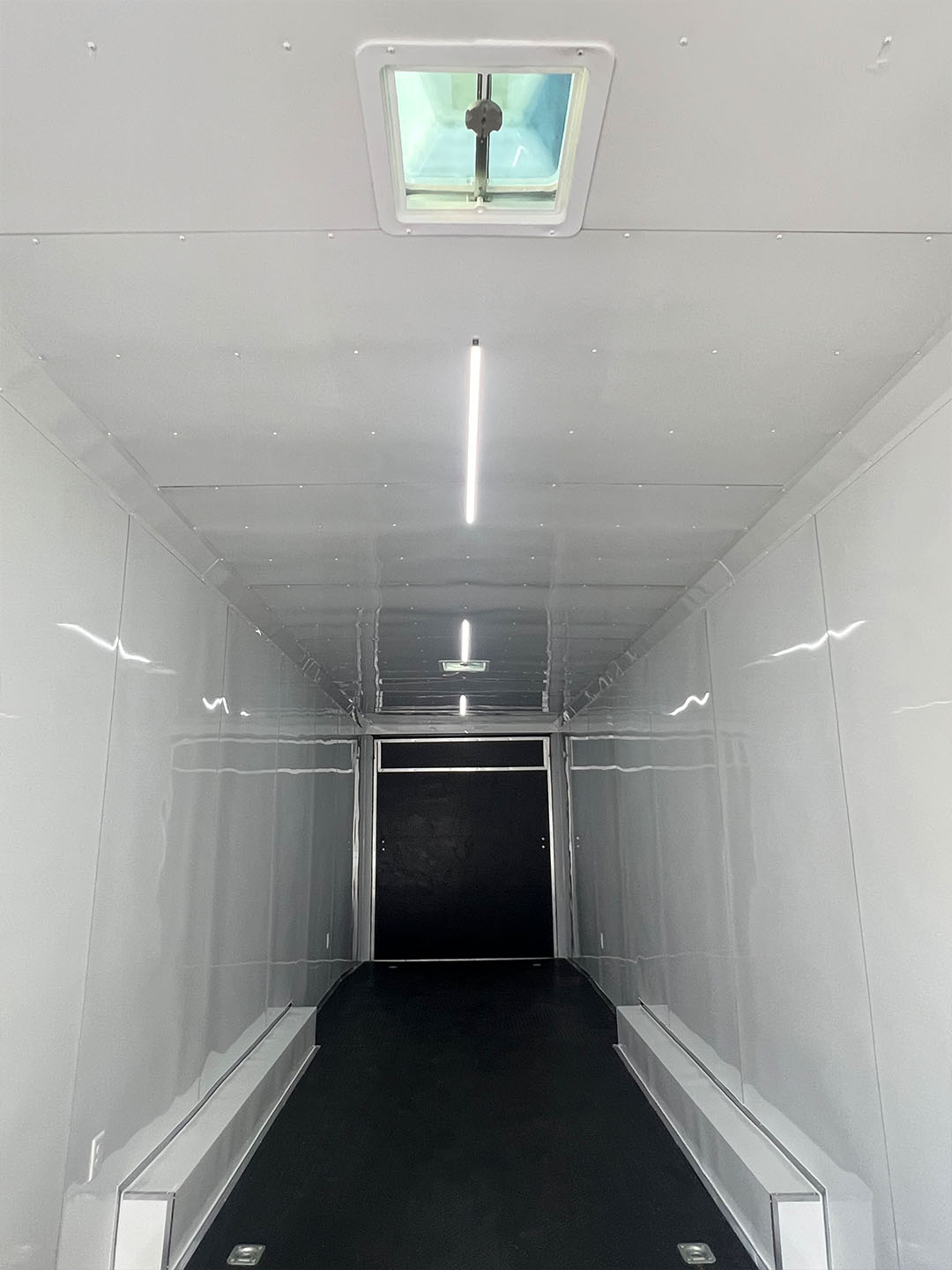 The image shows the inside of a white refrigerated truck with an open door, revealing a dark interior and a visible ventilation fan on the ceiling.