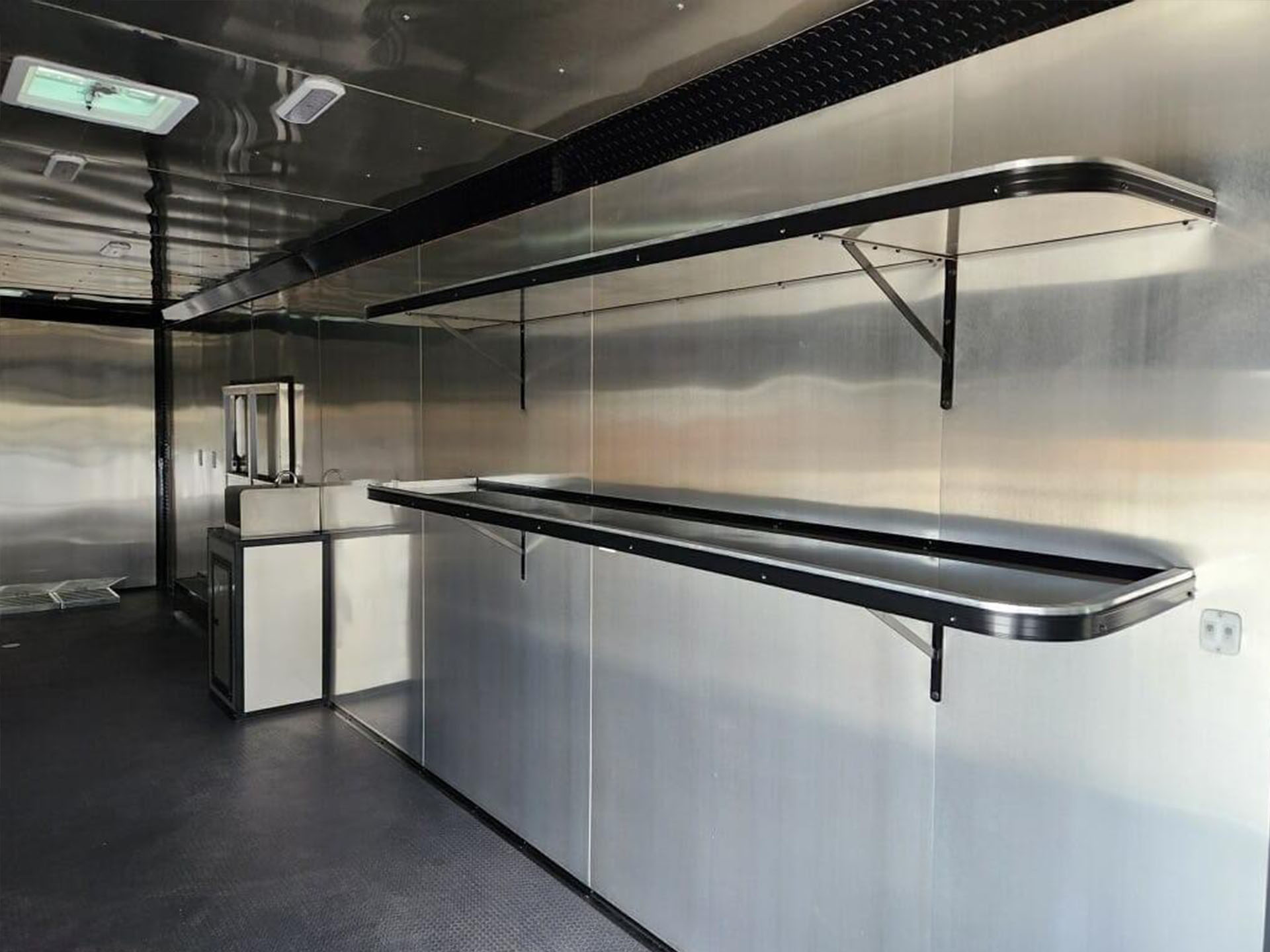 The image shows a large, metallic kitchen interior with stainless steel appliances and countertops.