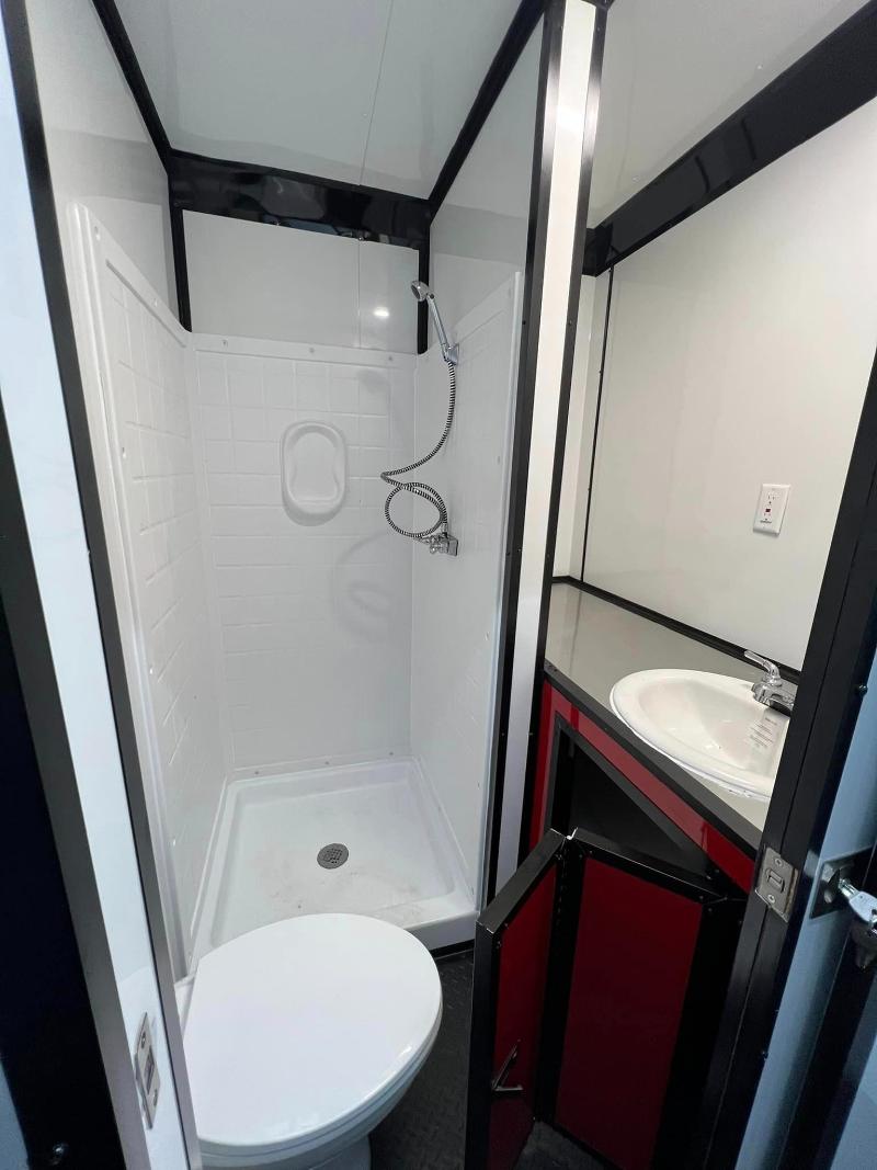 The image depicts a small bathroom with a toilet, sink, and shower stall, featuring white walls and tiled flooring.