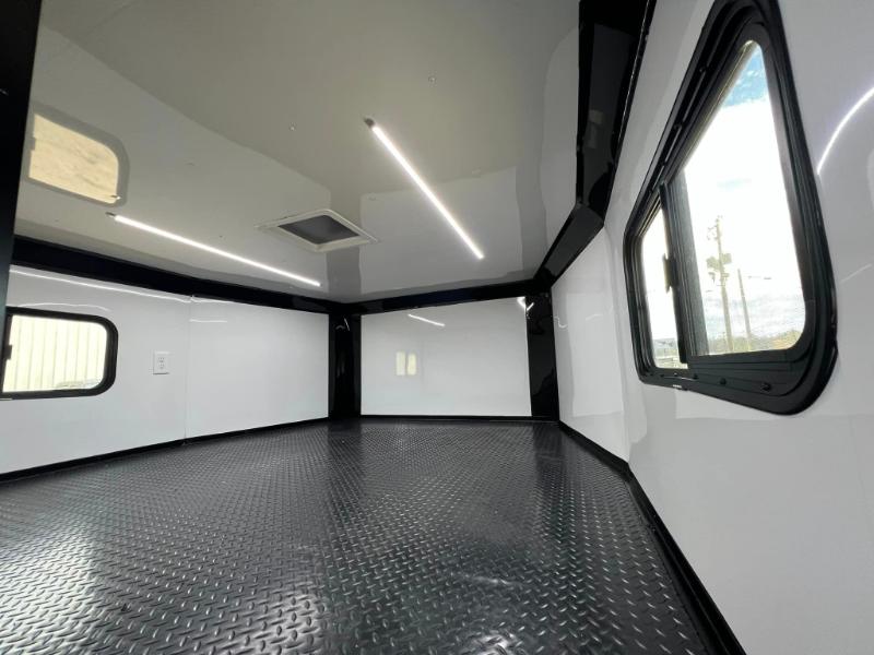 The image shows an interior view of a large commercial vehicle, likely a camper van or recreational vehicle, with a polished floor and a modern design featuring white walls and a dark ceiling.