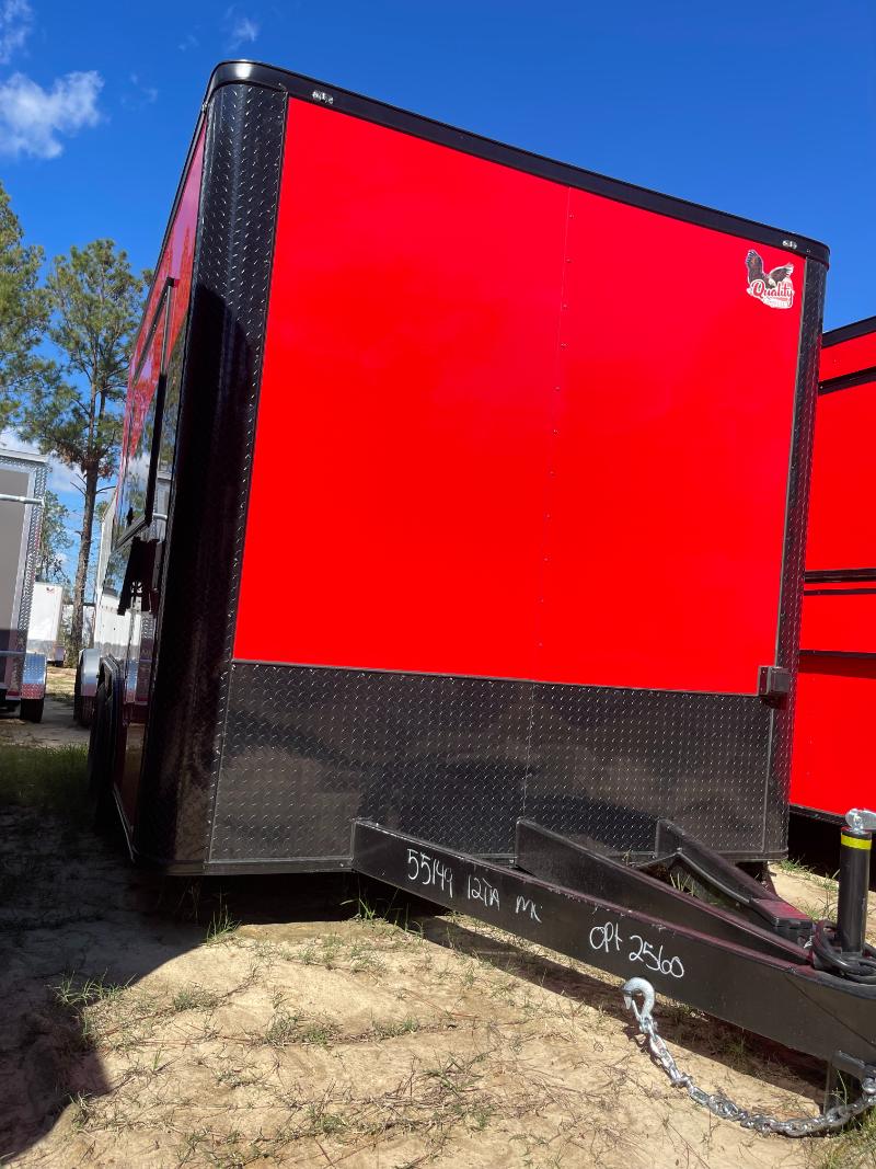 The image shows a large red trailer parked on grass with a clear sky in the background.