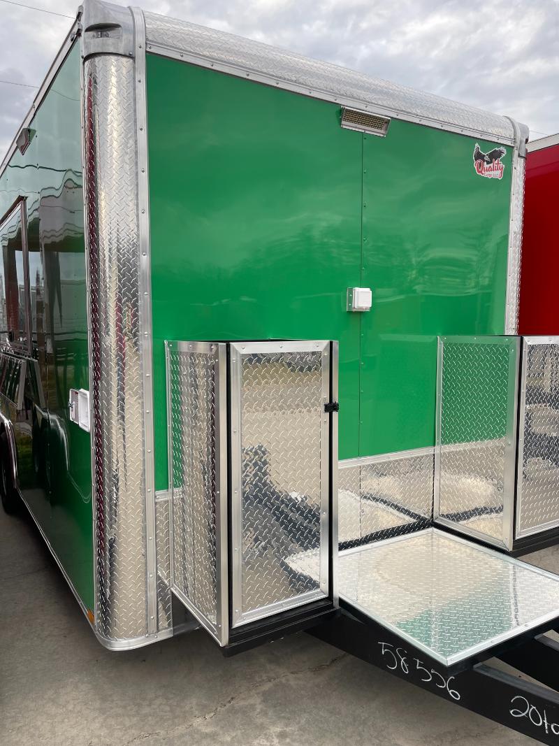 The image shows a large green and silver enclosed trailer with an open door, parked on a paved surface.