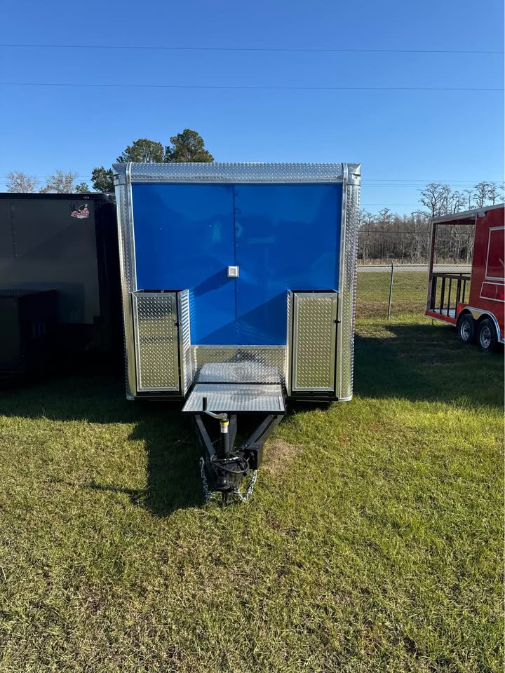 A blue portable toilet trailer parked on grass.