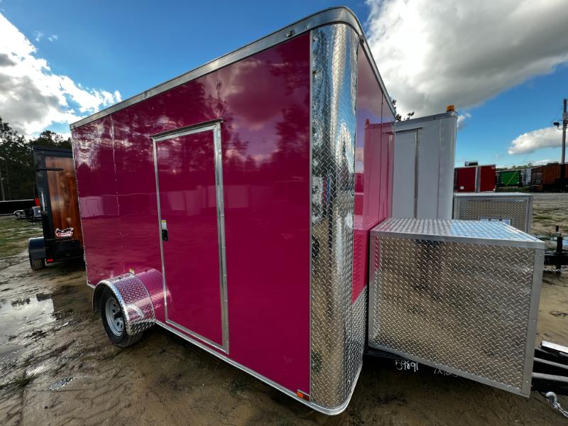 The image shows a pink trailer with a silver side panel parked on muddy ground.