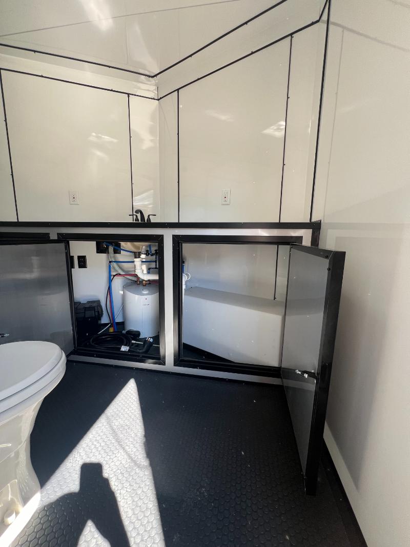 The image shows a compact bathroom area within a trailer home, featuring a toilet and storage cabinets with a stainless steel finish.
