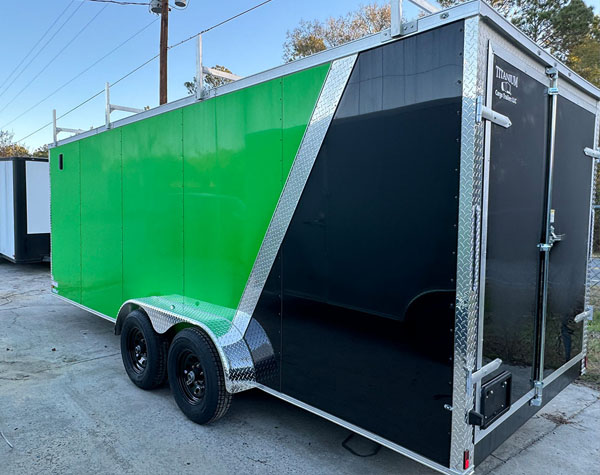 The image shows a large green and black trailer parked on a lot with a clear sky in the background.