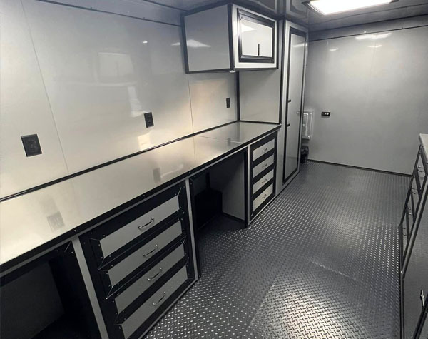 The image shows an interior view of a large commercial vehicle, specifically a food truck, with stainless steel countertops and storage units, featuring a clean and organized layout.