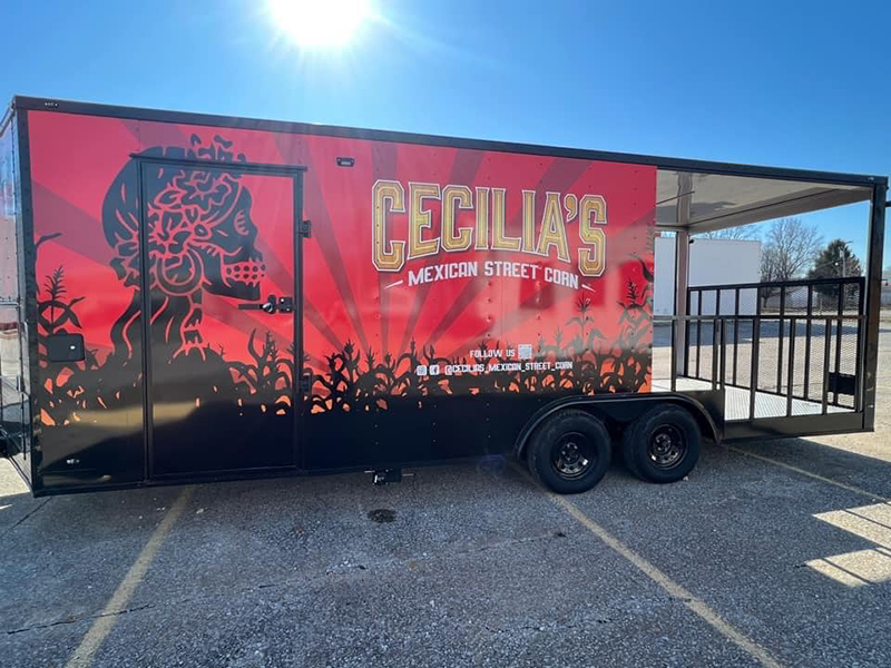 A red food truck trailer with a graphic design featuring a skull and crossbones on its side.