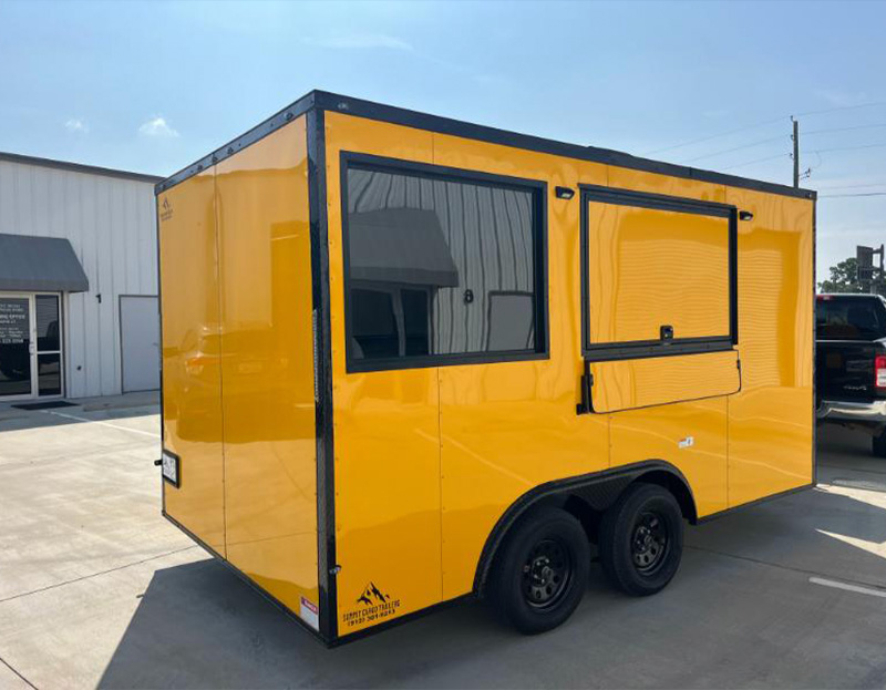 The image shows a bright yellow food truck parked on an asphalt surface with clear skies above.